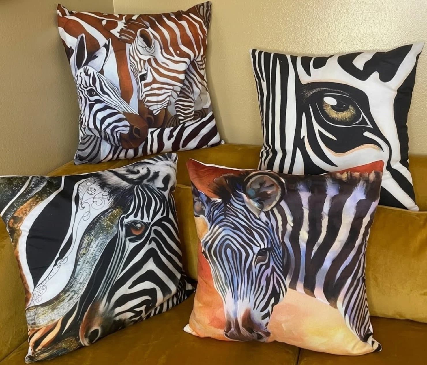 Four beige throw pillows with large black and white zebra stripe pattern and realistic horse eye detail.