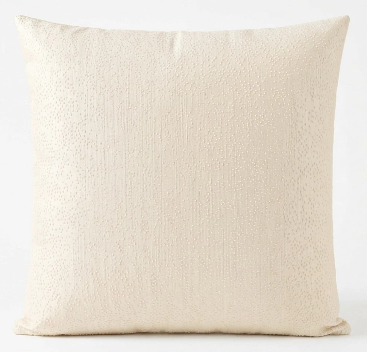 Square beige throw pillow with textured cream fabric, featuring subtle speckles and a smooth woven finish.