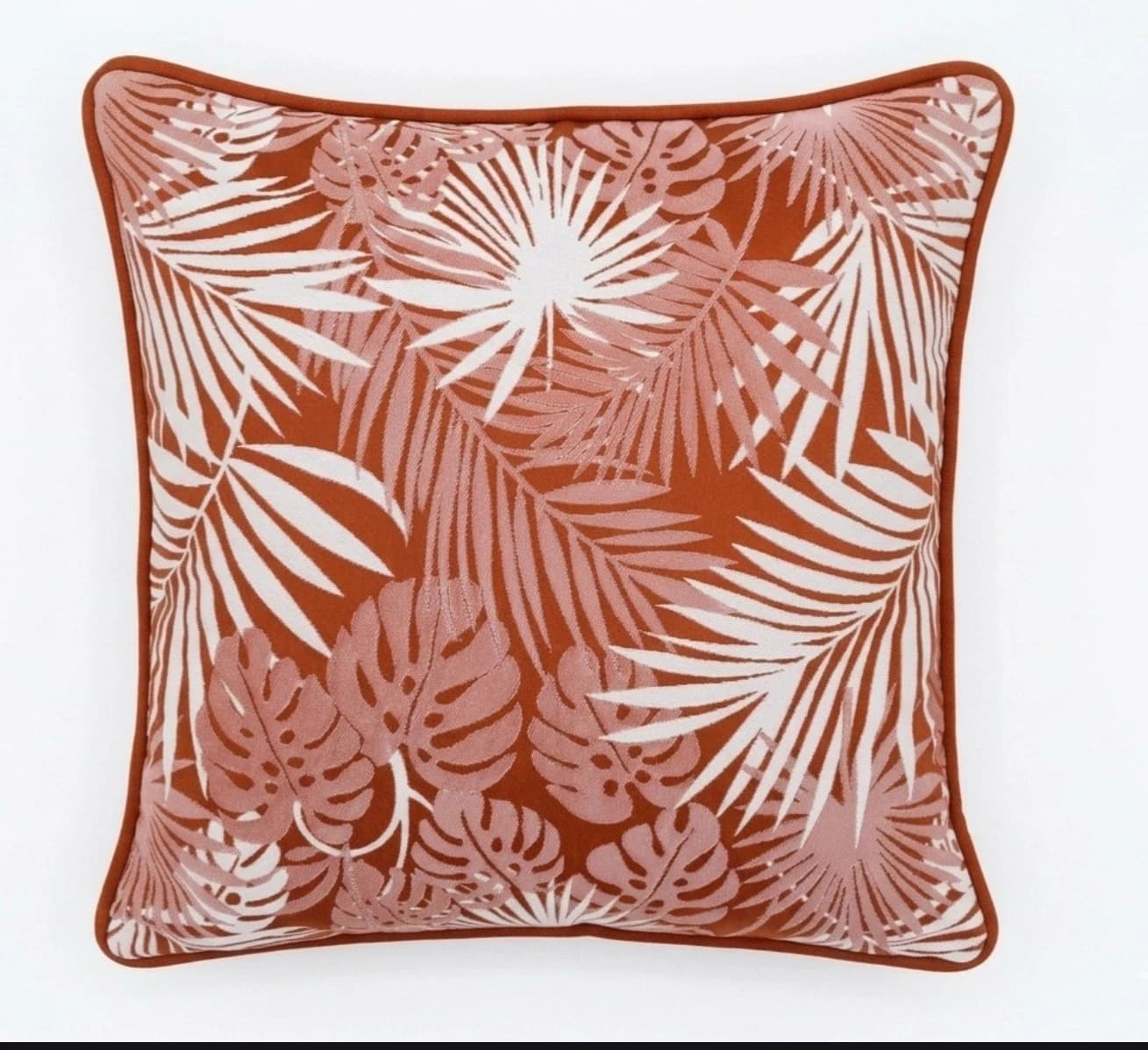 Terracotta square patio cushion with white tropical leaf print and matching fabric border on a plain light background.