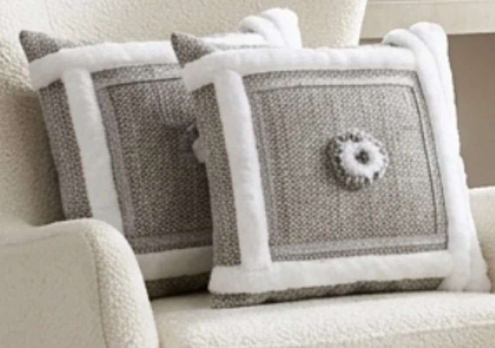 Gray and white tweed accent covers with plush white faux fur edges and central button-shaped motif on textured fabric.