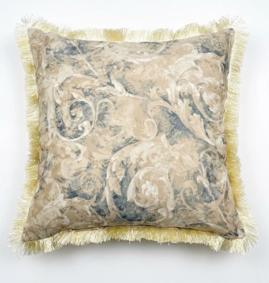 Beige square Damask scroll throw pillow with gold fringe trim and central grey scroll pattern on fabric.