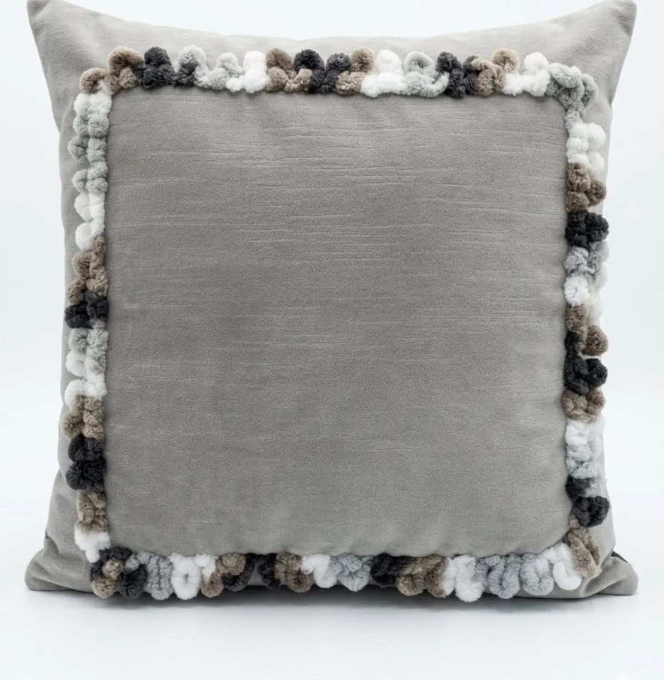 Gray velvet accent pillow cover with textured loop trim in white and brown, finished on a light gray background.